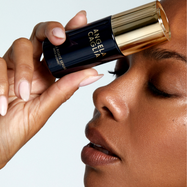 Close up black model face holding Cell Forte Serum bottle to face