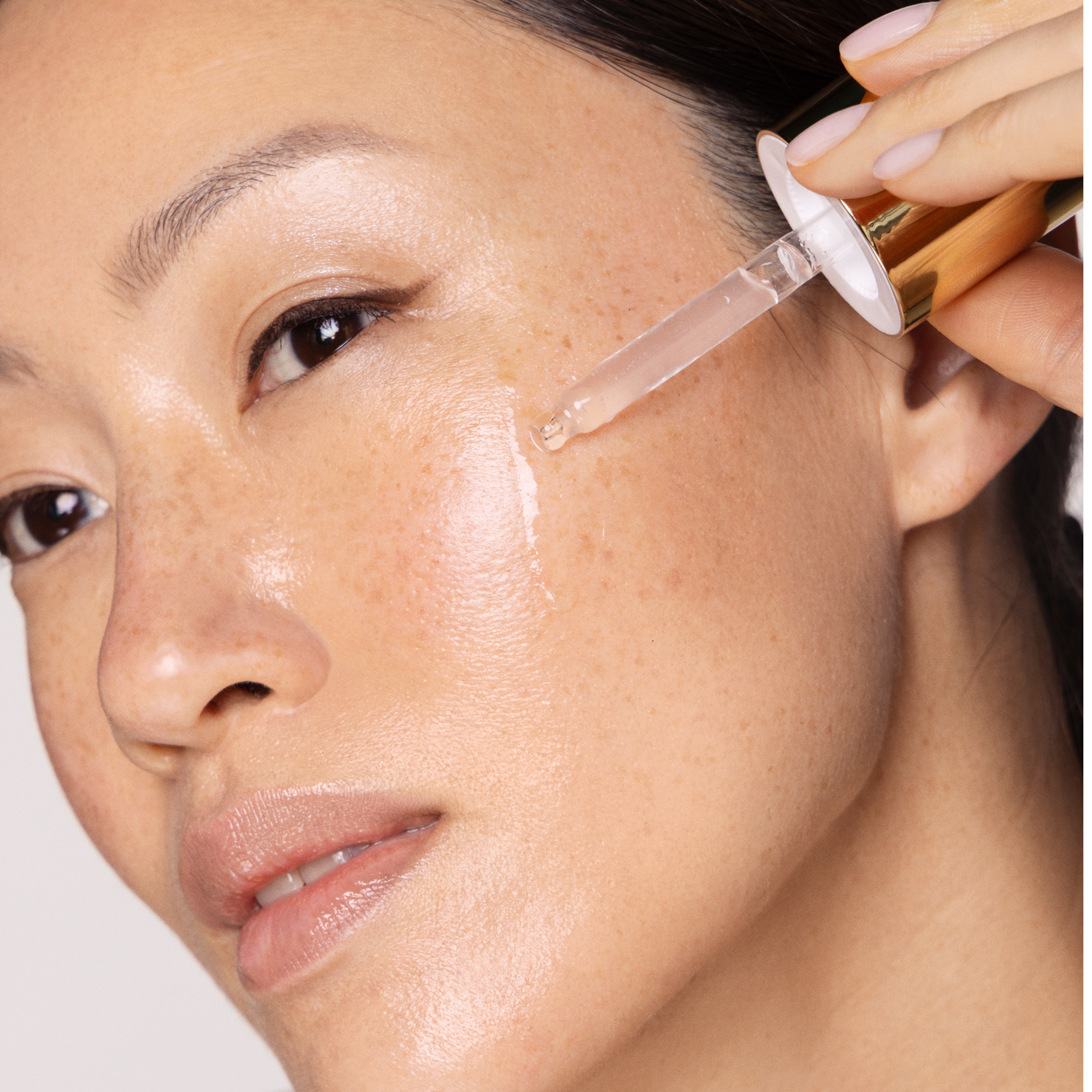 Asian model holding dropper to face.