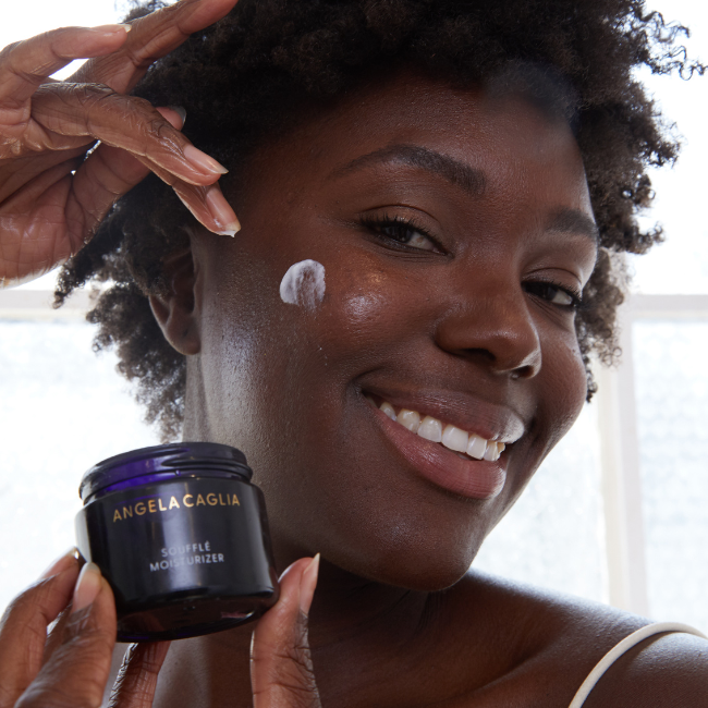 Black model close up applying Souffle Moisturizer to cheek