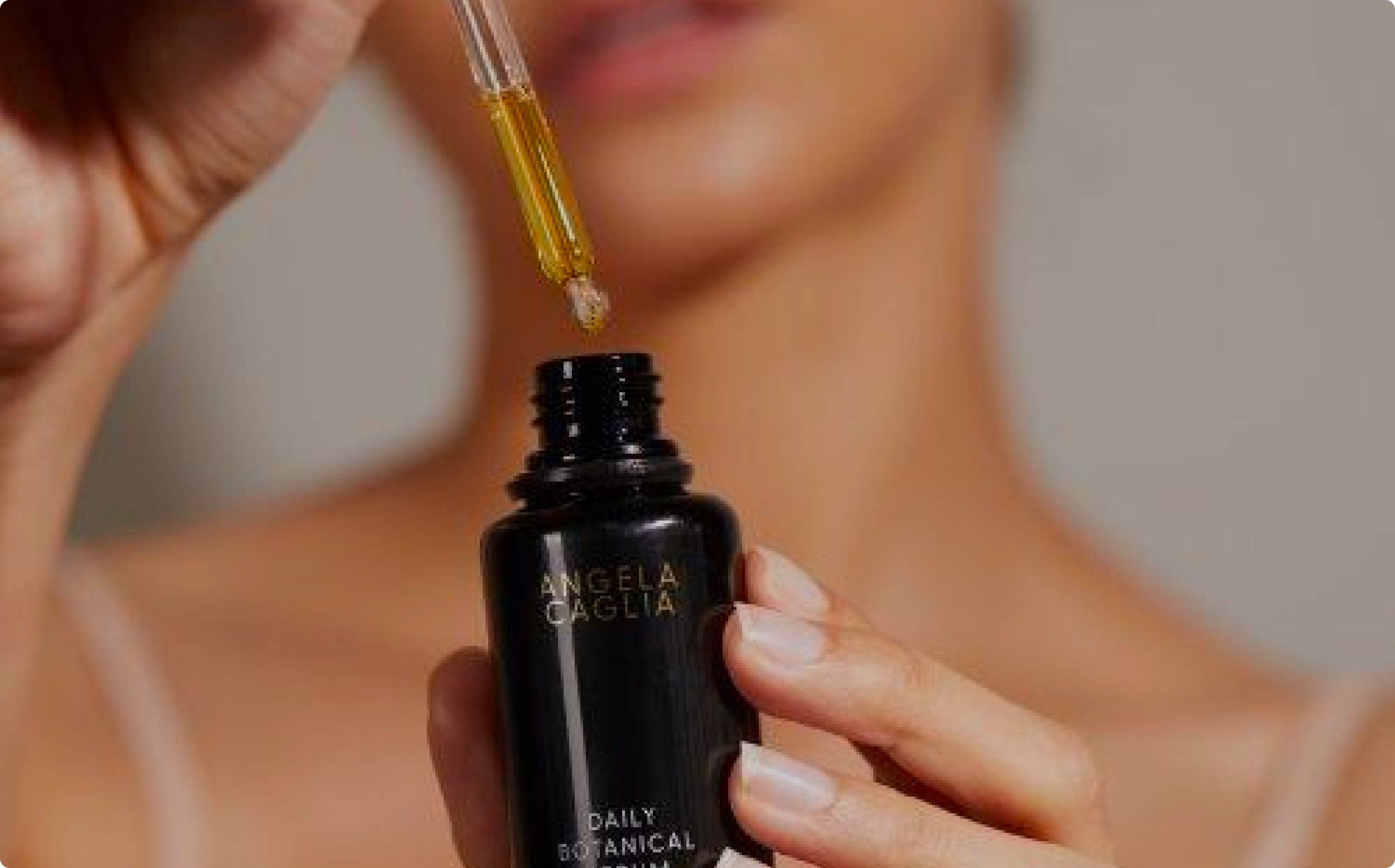 Bottle foreground, model background holding black serum bottle